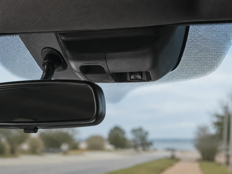 Close view from inside a car of the forward-facing camera module mounted behind the windshield next to the rearview mirror